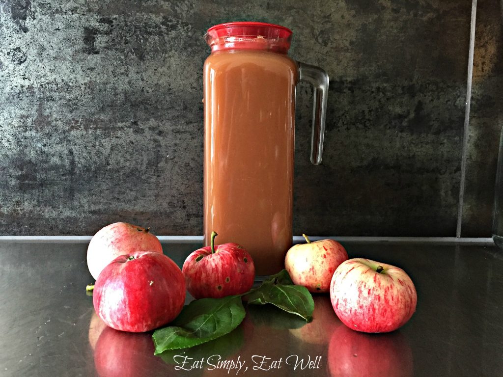 Glass of fresh organic apple juice with red and green apples in